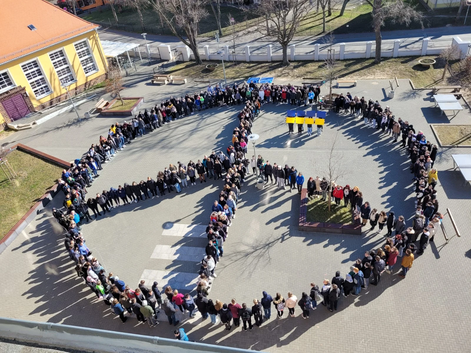 Die Schulgemeinschaft bildet ein großes Friedenszeichen auf dem Schulhof